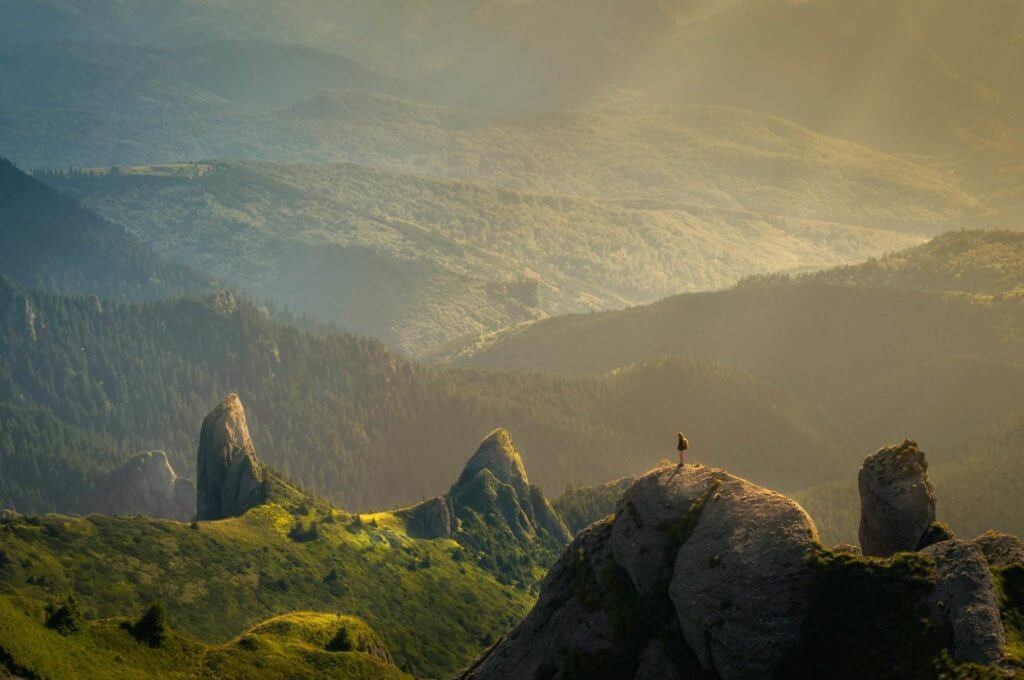Un homme se tient au sommet d’un rocher dans les montagnes, renouant avec l’énergie de la nature et diminuant son stress