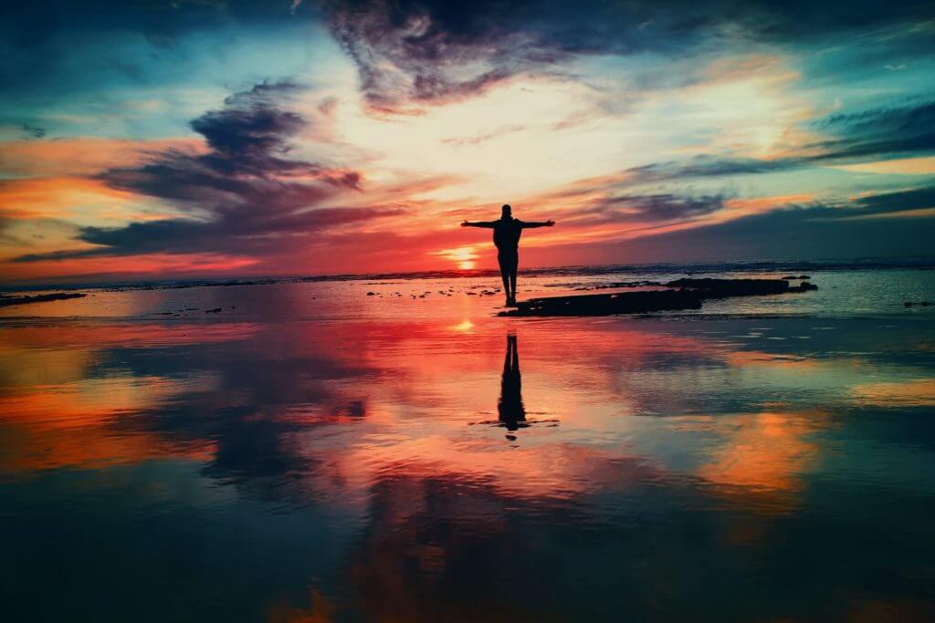 Un individu satisfait de sa vie sur une plage au coucher du soleil.