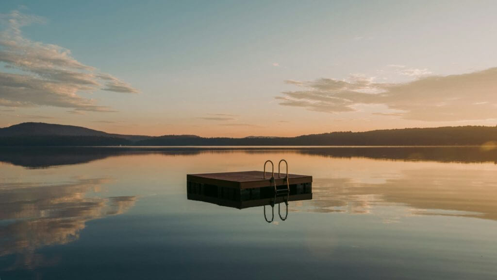Un quai serein au milieu d'un lac, entouré de paysages à couper le souffle au coucher du soleil.