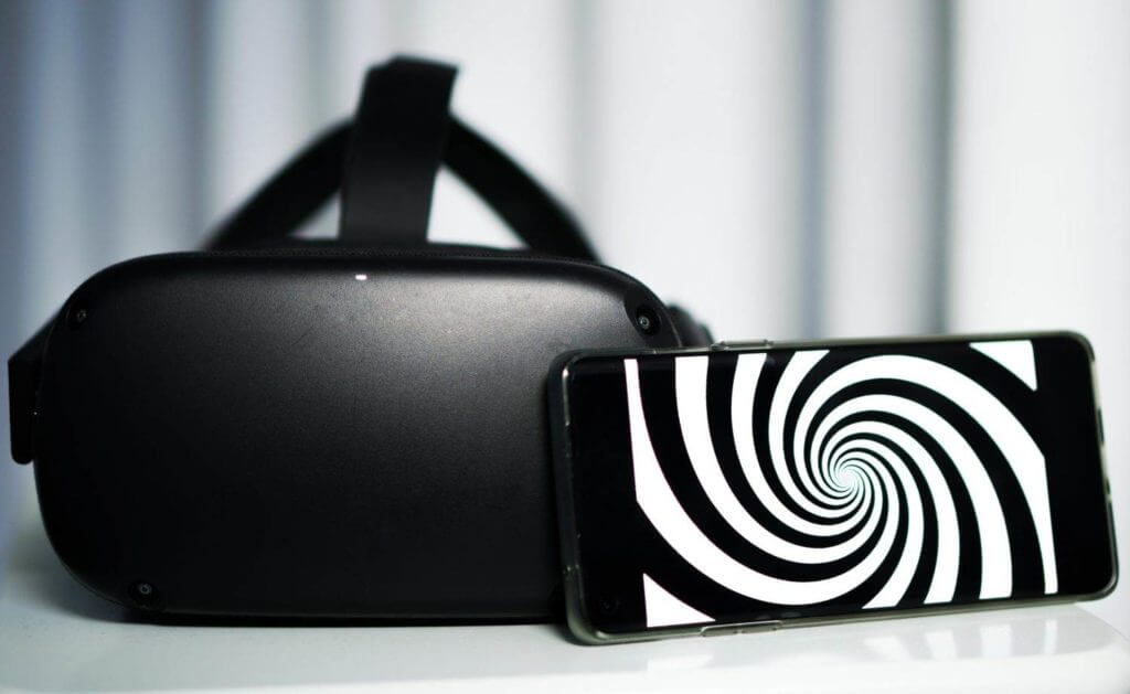 Un casque de réalité virtuelle (VR) noir et blanc associé à un téléphone portable.