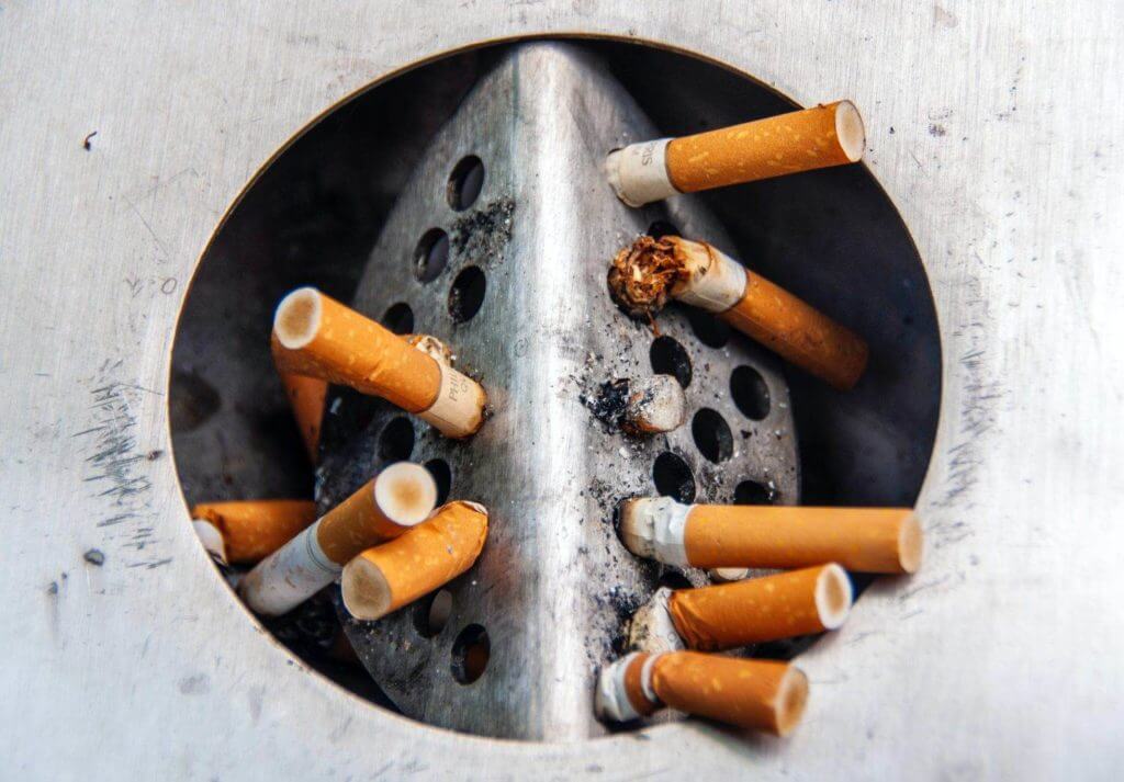 Un groupe de cigarettes dans un cendrier métallique, une aide pour arrêter de fumer.