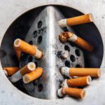 Un groupe de cigarettes dans un cendrier métallique, une aide pour arrêter de fumer.