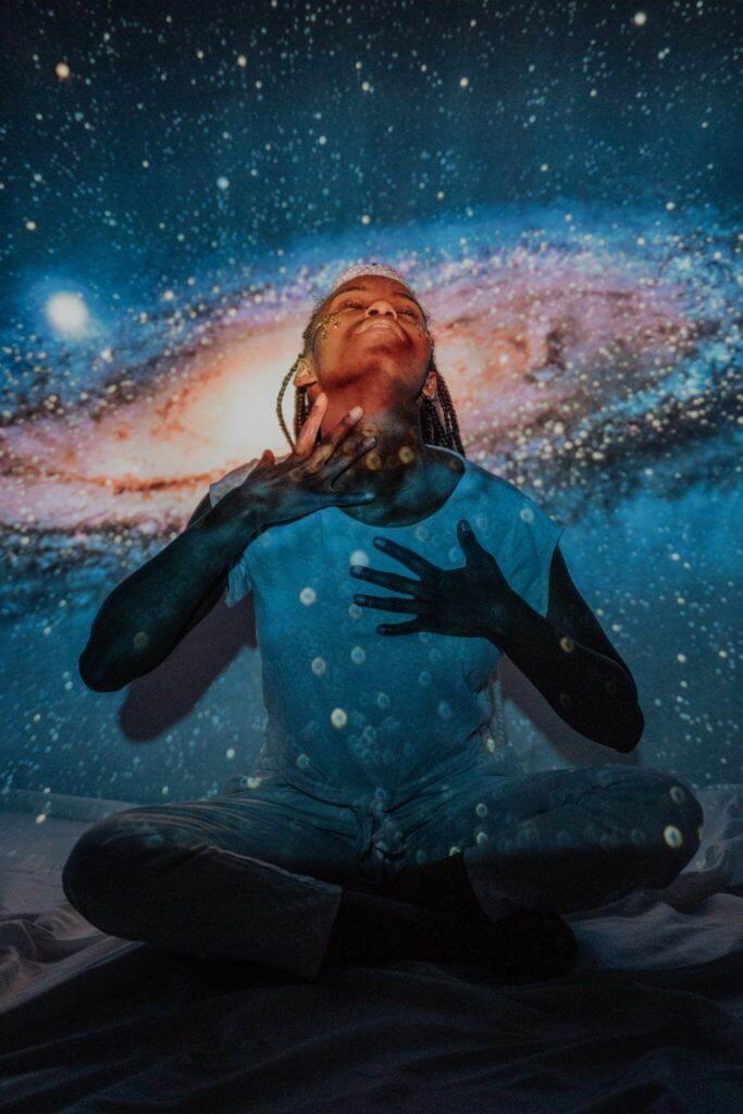 Une femme en état de méditation profonde vivant l’hypnose, complètement immergée devant un ciel étoilé.