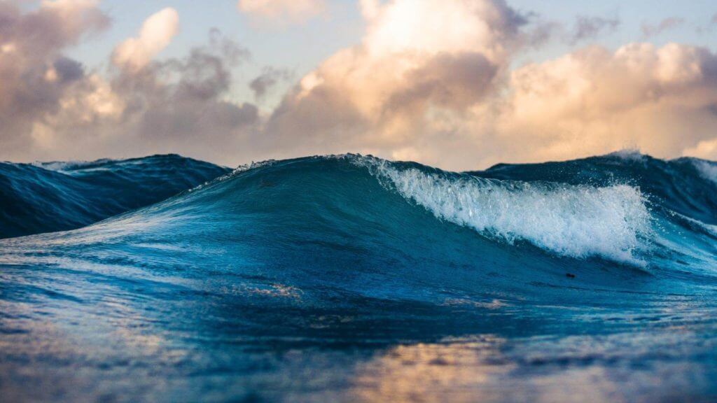Une grande vague s'écrasant sur l'océan au coucher du soleil tout en créant un effet de sommeil envoûtant.