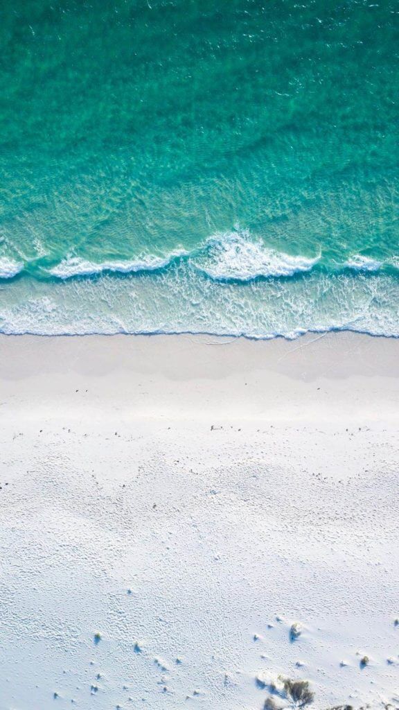 Une vue aérienne d'une plage de sable blanc et d'eau bleue, créant une ambiance sereine idéale pour favoriser la détente et un sommeil paisible.
