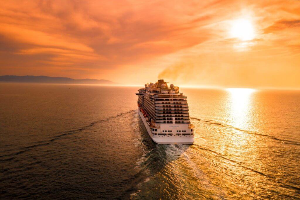 Un grand bateau de croisière naviguant sur l'océan au coucher du soleil, offrant un décor serein et majestueux à ceux qui cherchent à se détendre pendant leurs vacances.