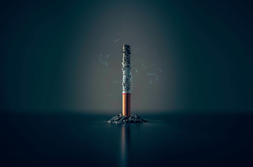 Une image de cigarette sur fond sombre, soulignant l’attrait hypnotique du tabac.