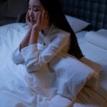 Une jeune femme asiatique souffrant d'angoisse alors qu'elle est couchée la nuit.