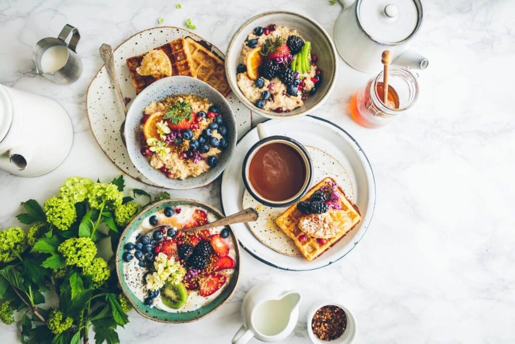 Un délicieux petit-déjeuner composé de gaufres et de fruits, joliment présentés sur une table en marbre.