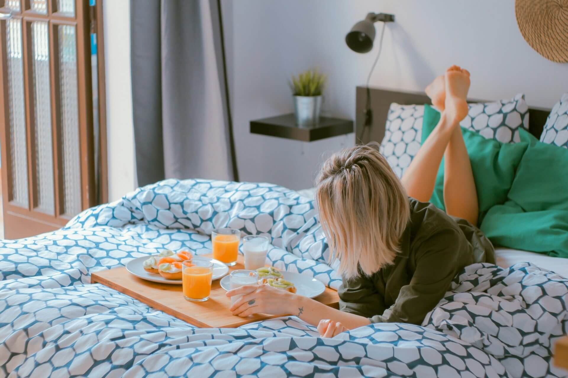 Une femme est allongée au lit avec un plateau de petit-déjeuner tout en explorant les bienfaits de l'hypnose pour perdre du poids.