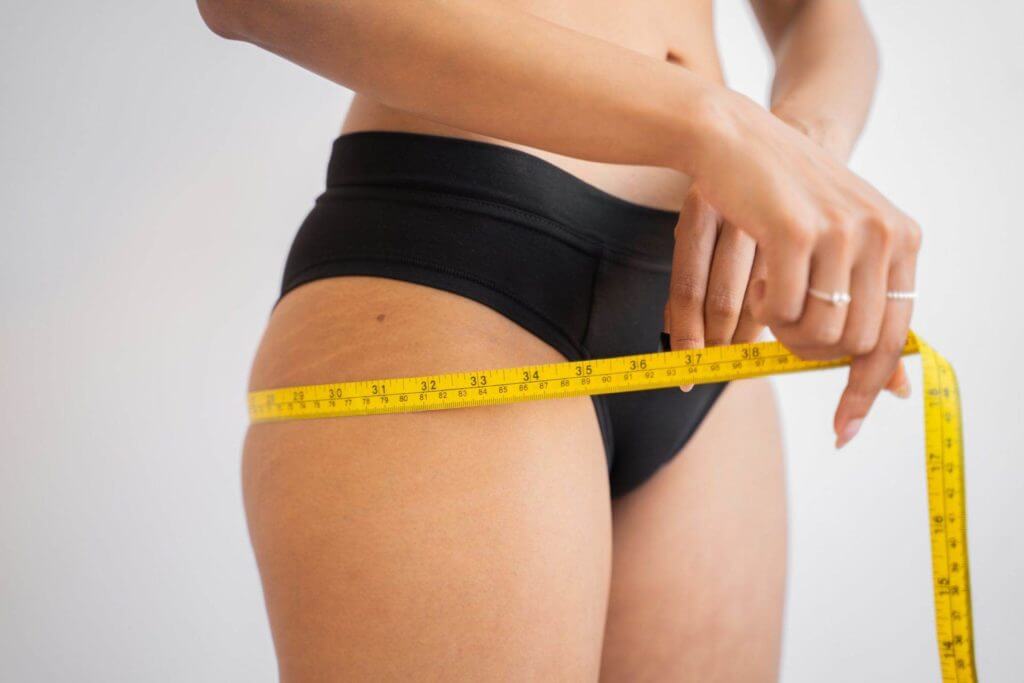 Une femme utilise un ruban à mesurer pour mesurer sa taille dans ses efforts pour maigrir.