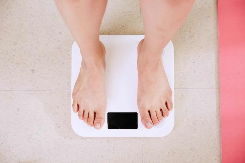 Les pieds d'une femme debout sur une balance pendant qu'elle est soumise à l'hypnose pour maigrir (perdre du poids).