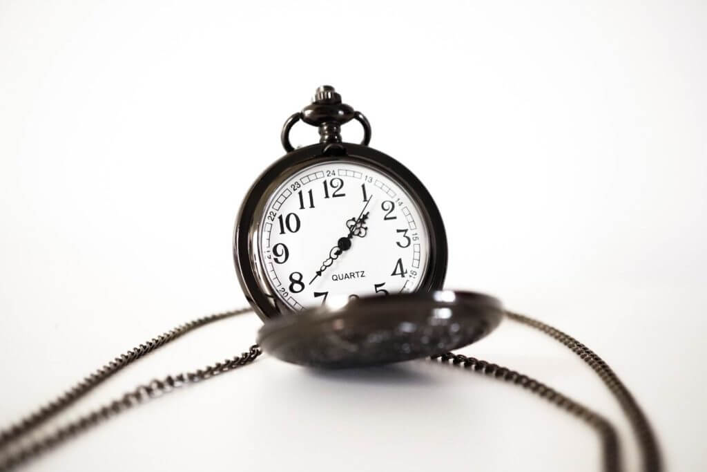 Une montre de poche hypnose avec une chaîne sur une surface blanche.