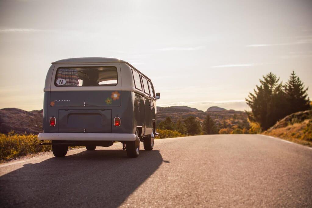 Un bus VW bleu et blanc circulant sur une route de campagne, favorisant la santé mentale et le bien-être.