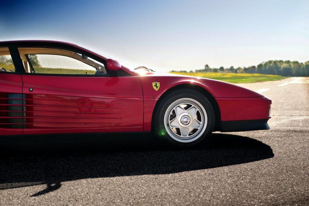 Une voiture de sport Ferrari rouge est garée sur une route.