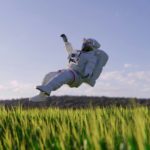 Un homme en combinaison spatiale volant à travers un champ d’herbe.
