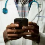 Un médecin en blouse blanche tenant un téléphone portable.