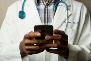 Un médecin en blouse blanche tenant un téléphone portable.