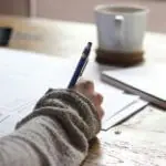 Une personne est assise à une table avec un stylo et du papier.