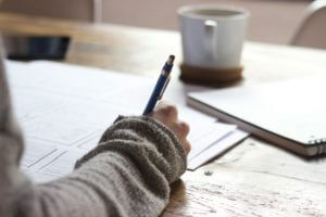 Une personne est assise à une table avec un stylo et du papier.