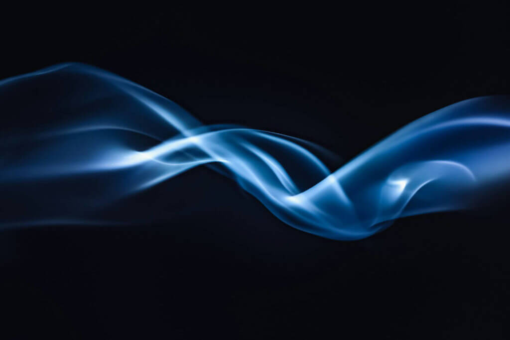 Image abstraite d’un motif de fumée bleue fluide et fluide personnalisé sur un fond sombre.